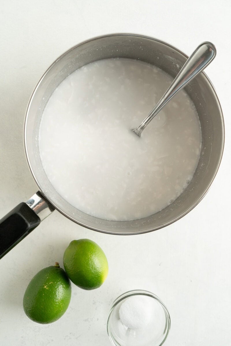 Water and coconut milk being mixed in a pot.