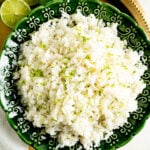 Pic of a bowl of coconut rice from overhead on a gold serving tray with limes.