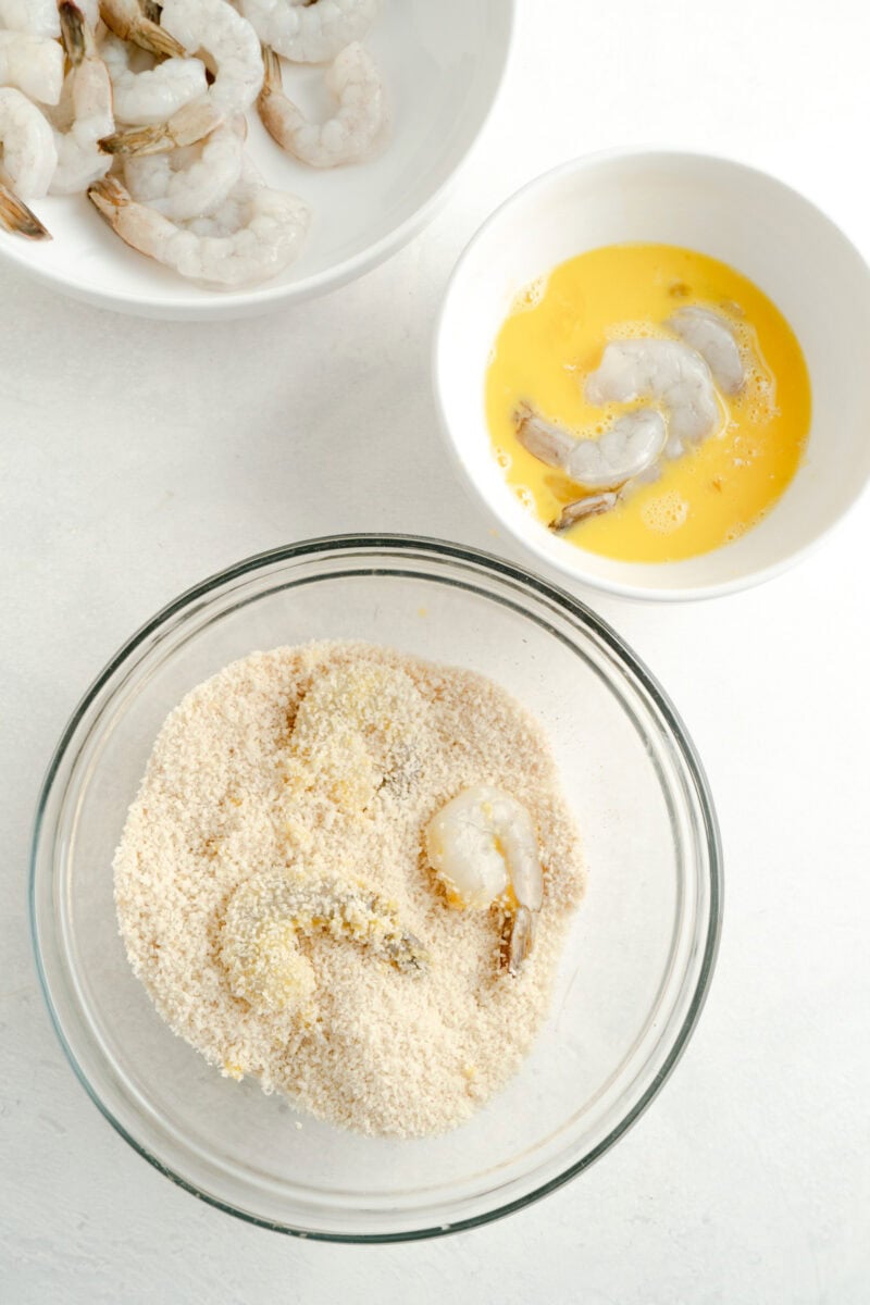 Shrimp being tossed in beaten eggs and then dredge in panko bread crumbs.