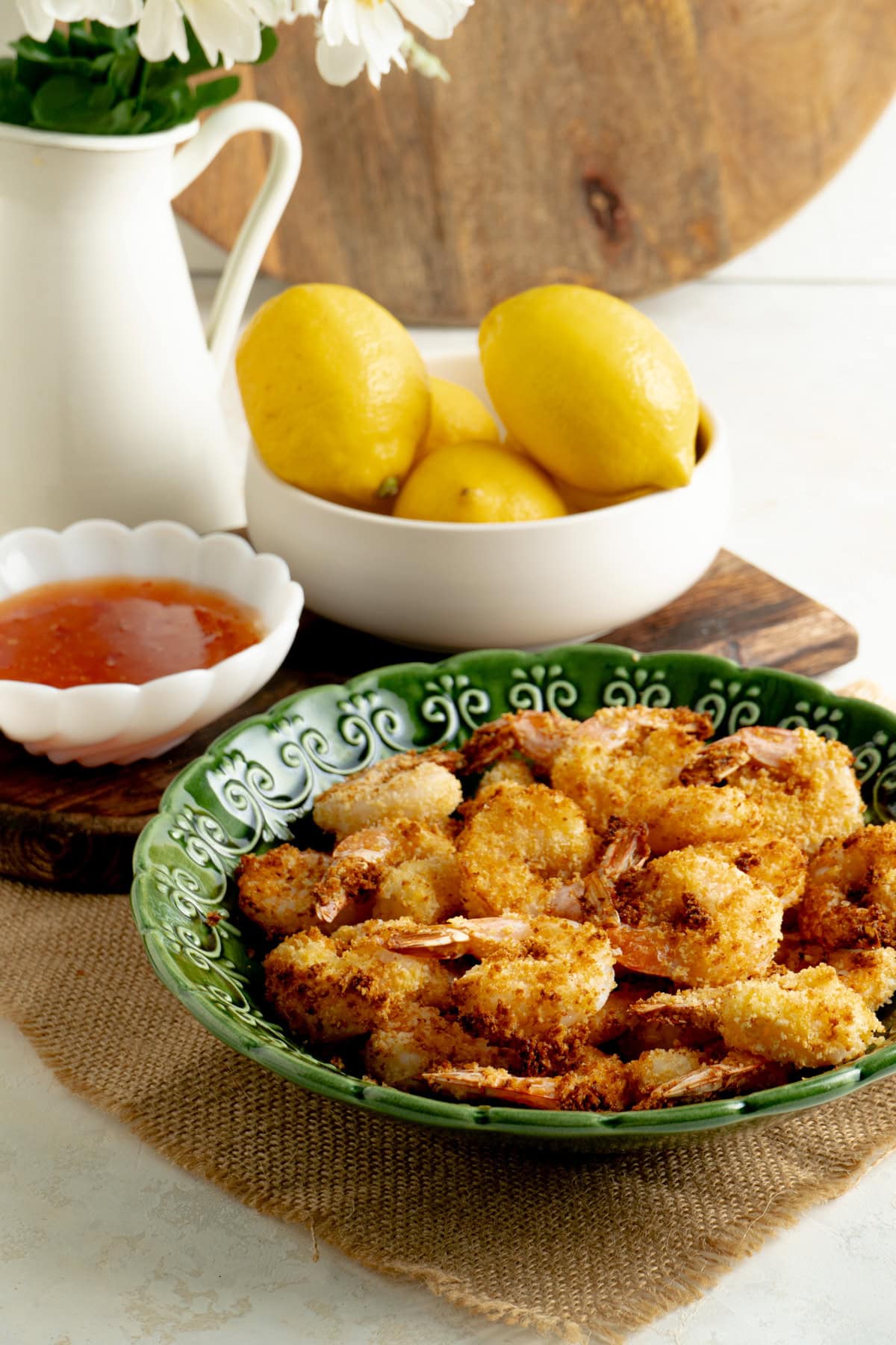 A bowl of 10 minute air fryer shrimp on a dinner table with dipping sauce and lemons.