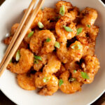 Overhead shot of bang bang shrimp in a bowl with chopsticks.