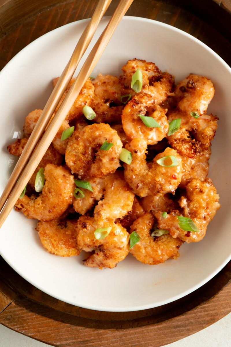 Overhead shot of bang bang shrimp in a bowl with chopsticks.