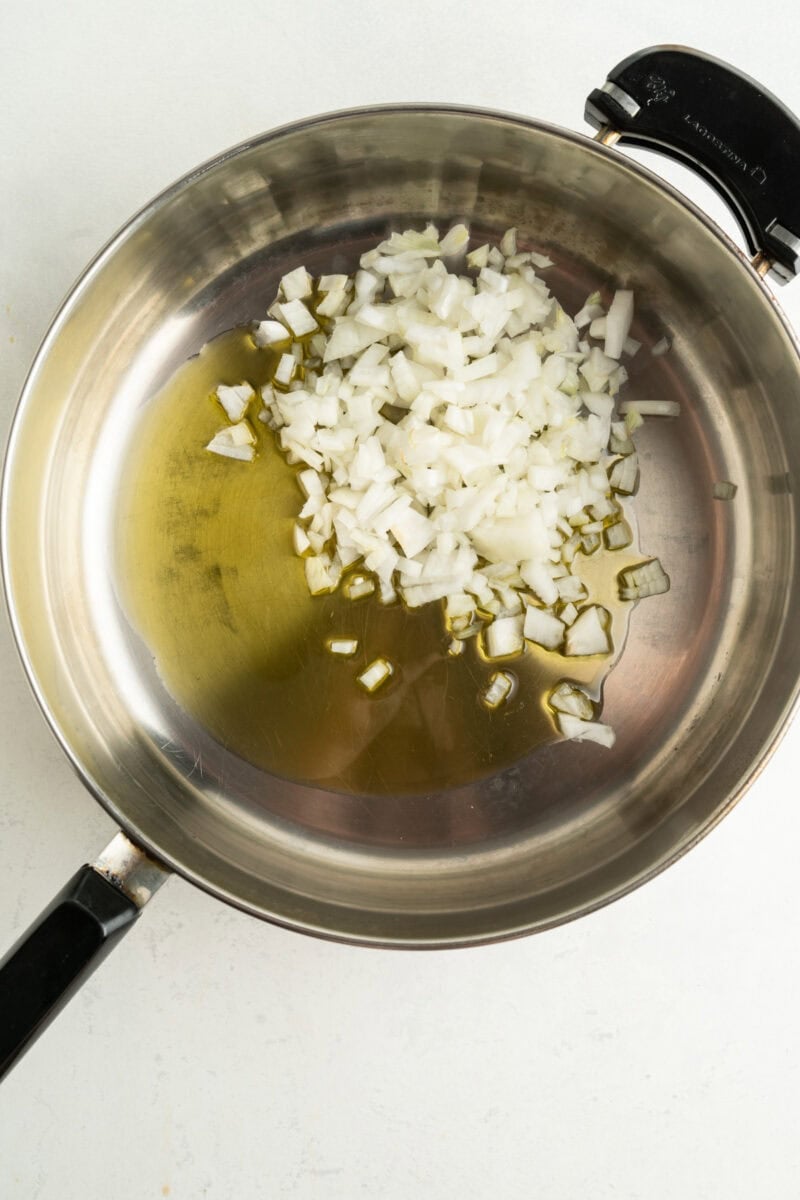 Olive oil and onions sauteed in a pan.