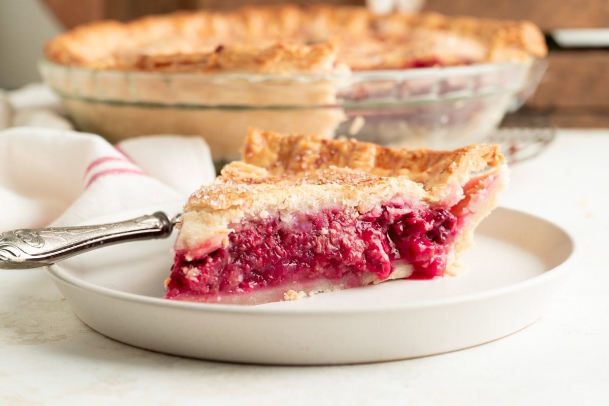 A slice of rasberry pie on a plate sideways.