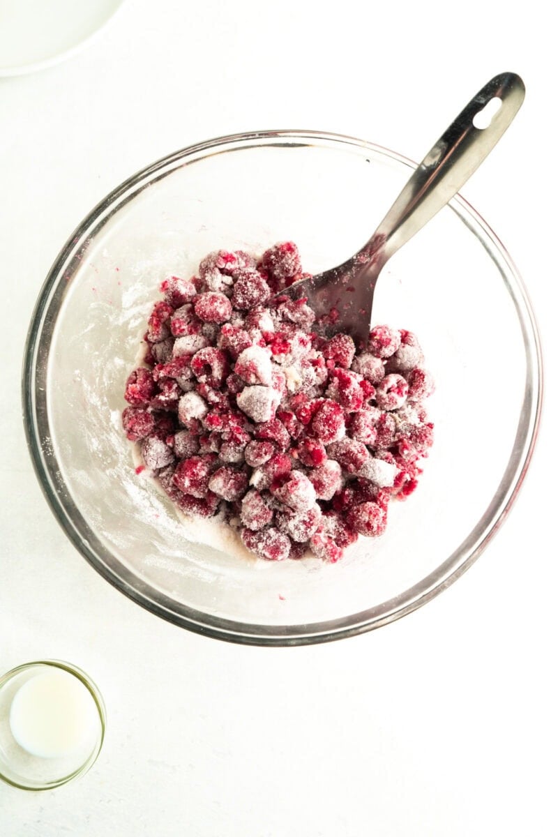 A bowl of raspberries mixed with flour and sugar.