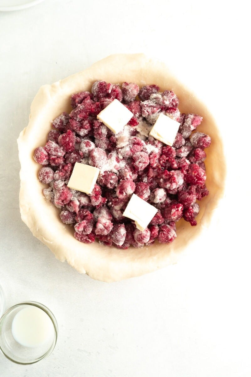 Raspberries in a pie crust dotted with cold butter.