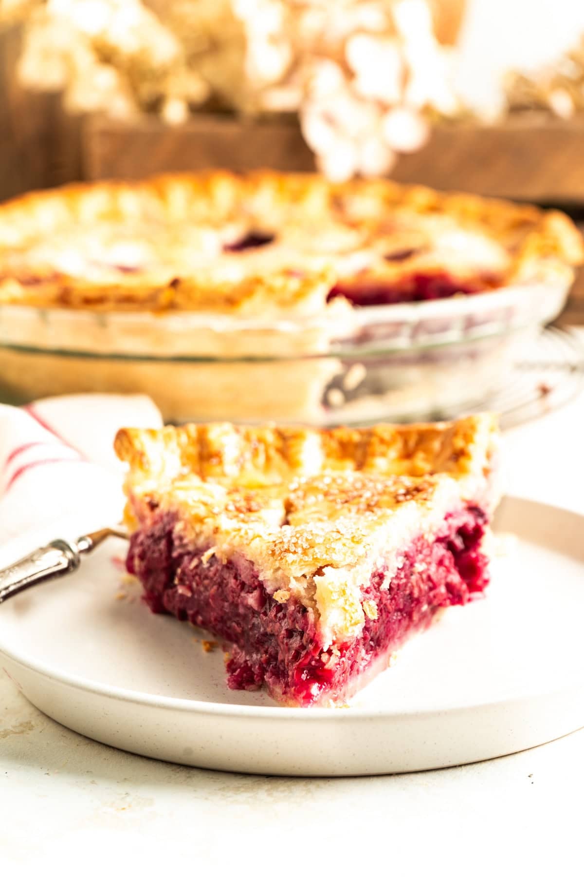 A head on shot of a slice of raspberry pie on a plate.