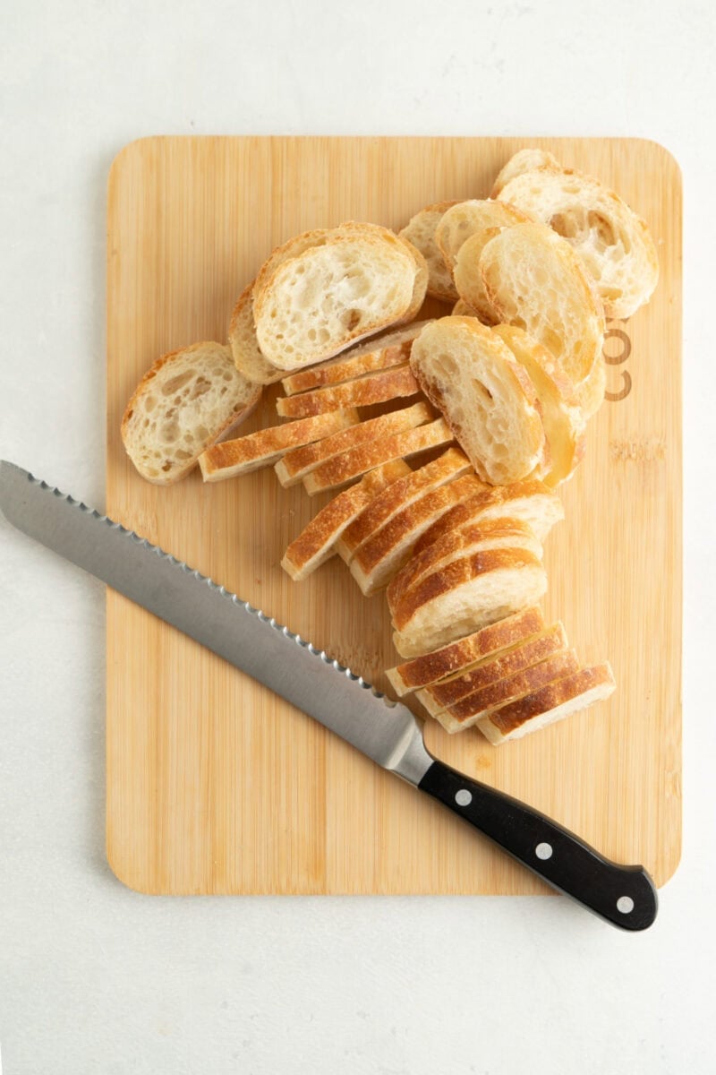 A baguette being thinly sliced.