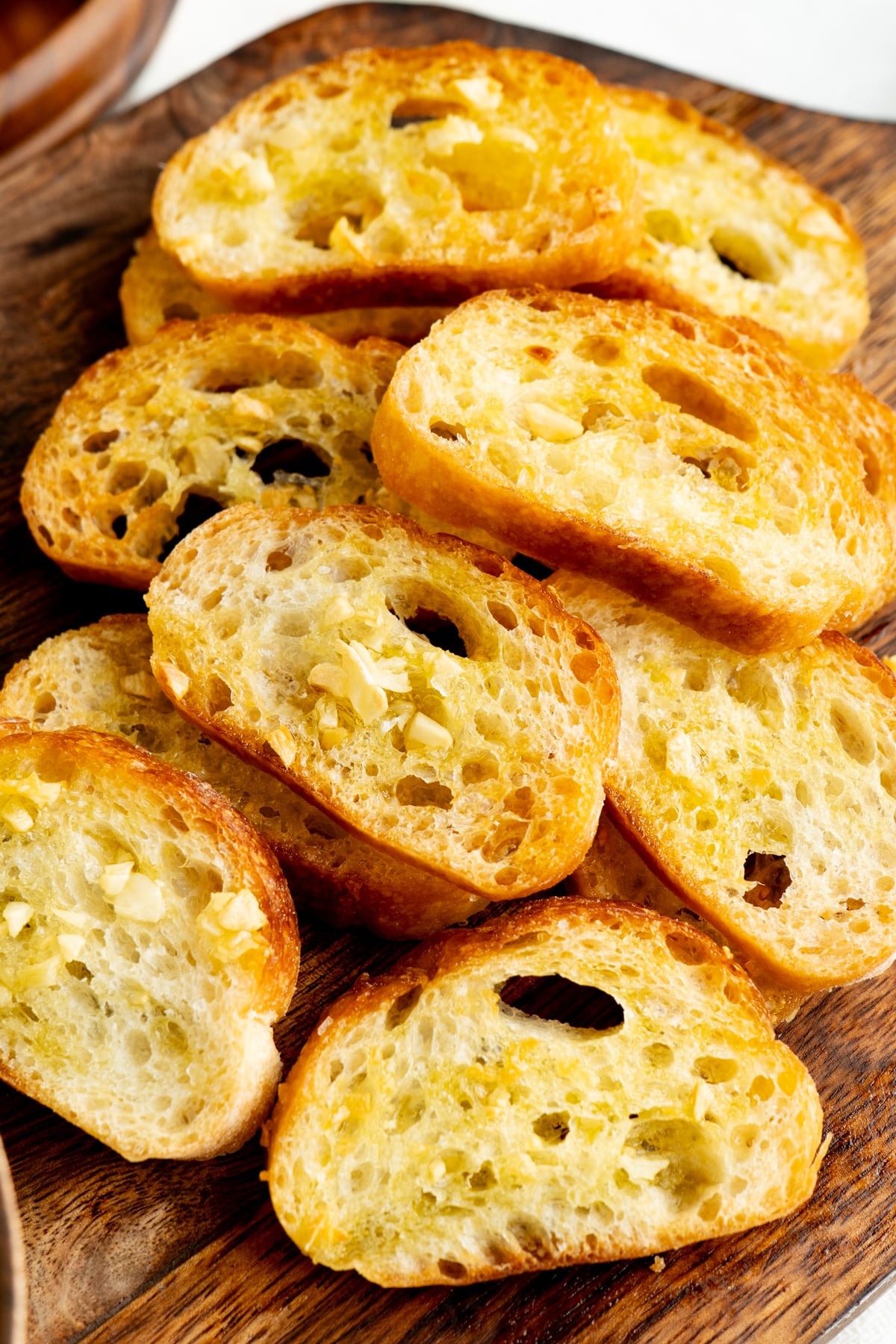 A pile of crostini crackers on a cutting board.