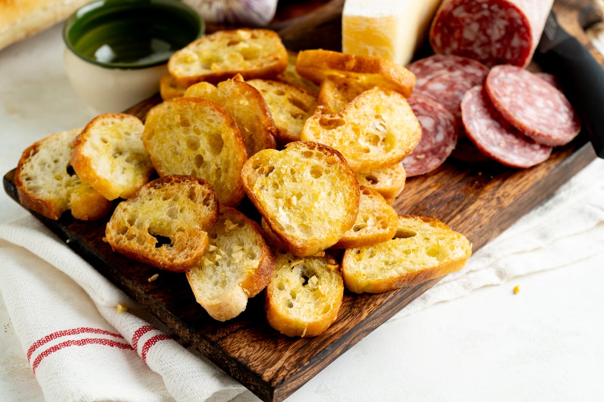 A platter of crostini, salami and cheese.