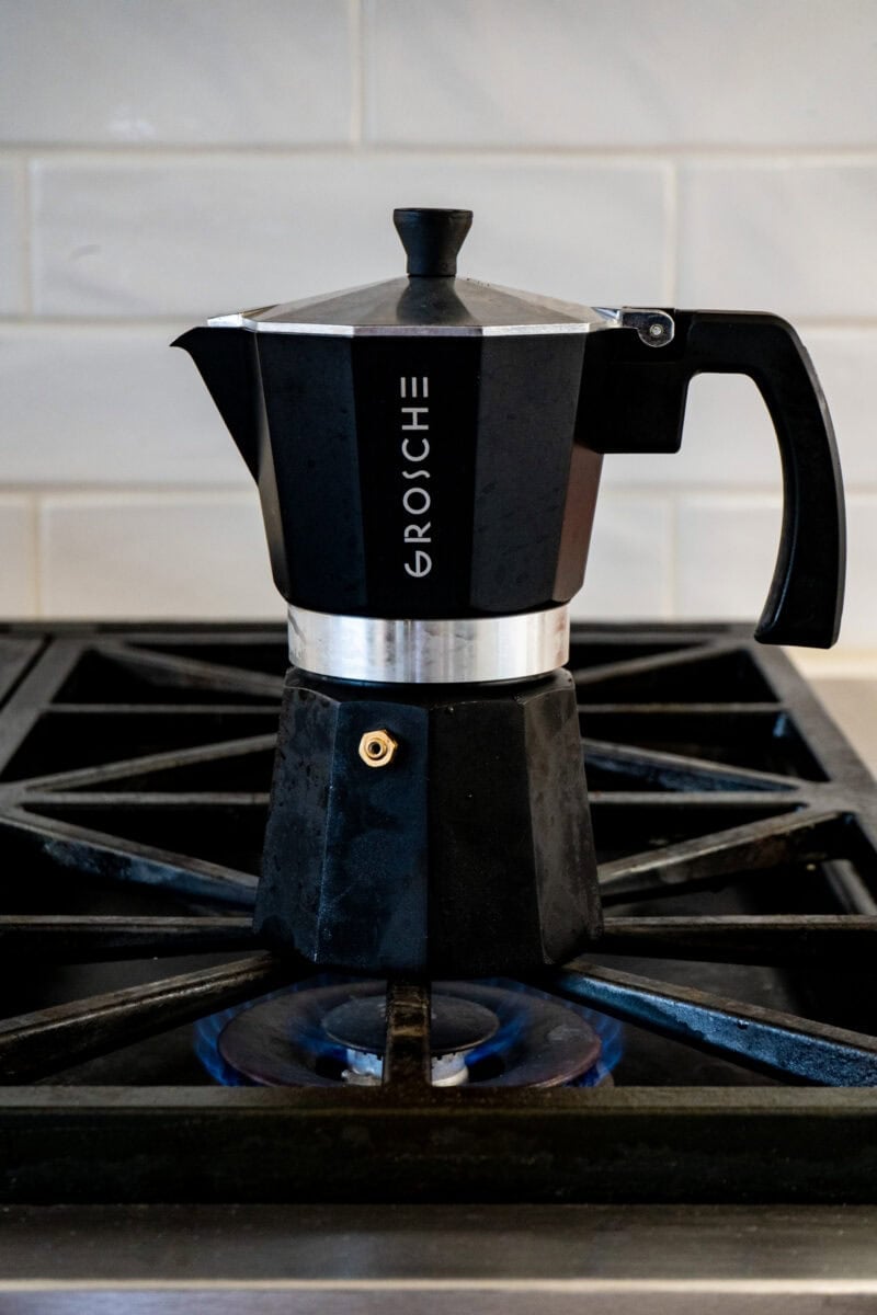 An espresso pot on a gas burner.