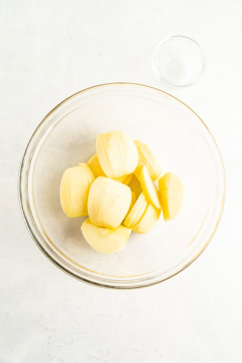 Peeled apples being tossed in lemon juice.