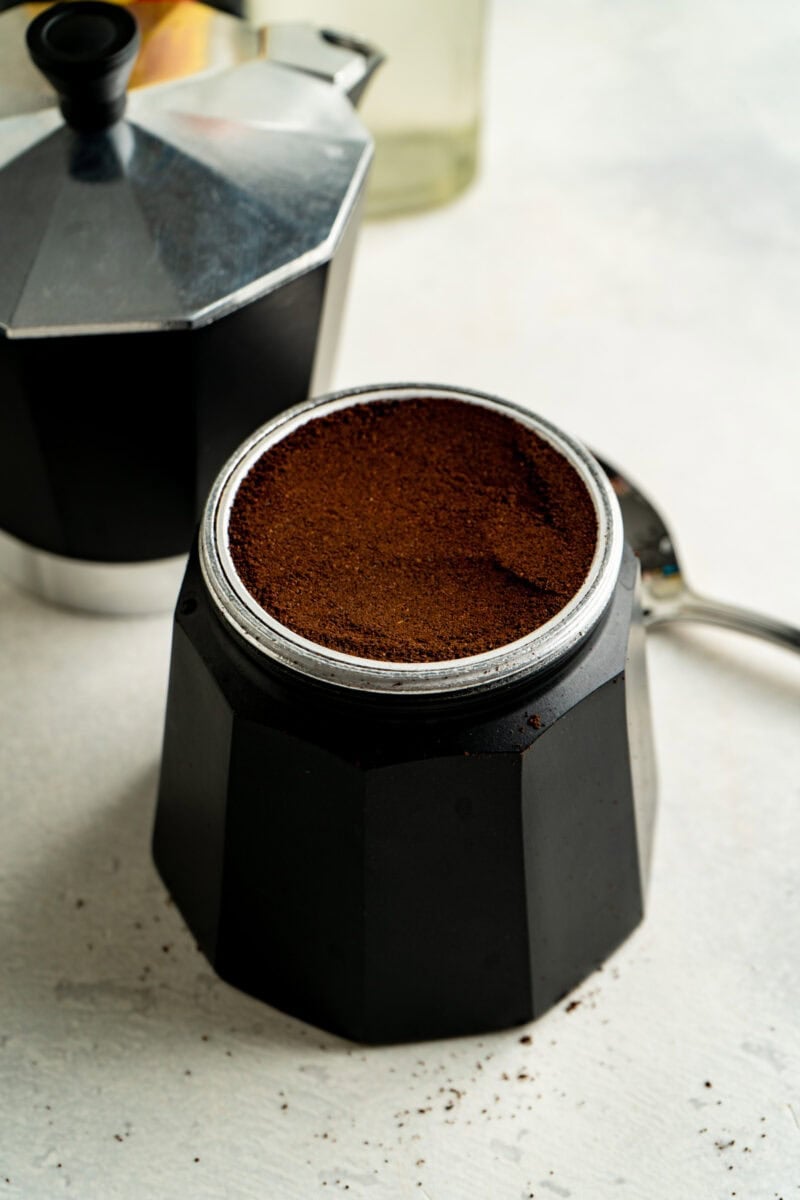 The filter funnel of an espresso pot filled with espresso powder.
