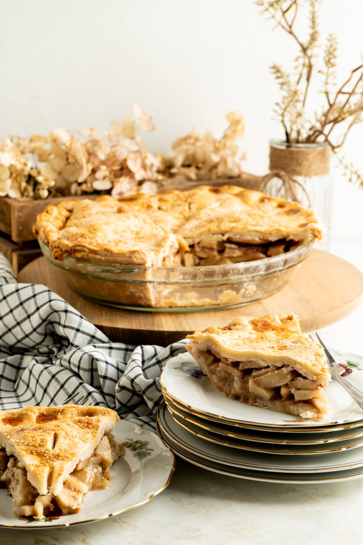 An apple pie and two slices on a fall table.