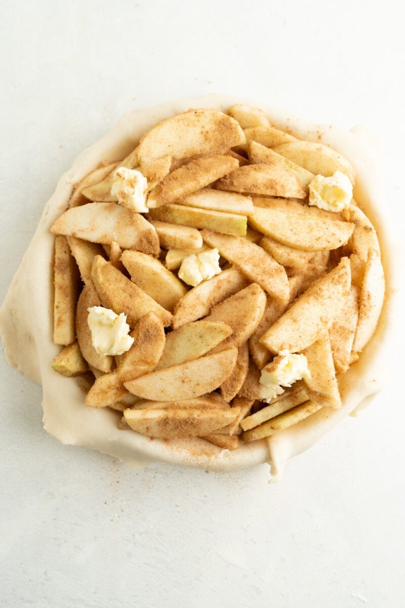 Seasoned apples inside an uncooked pie shell.