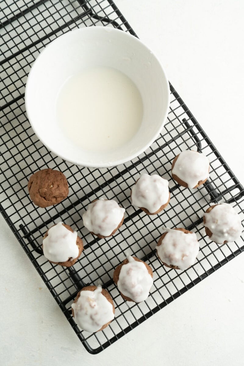 Cookies being iced on a cooling rack.