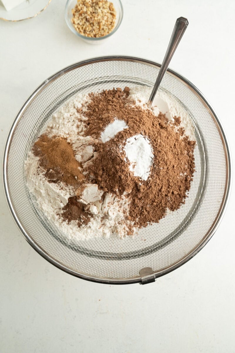 Flour and spices being mixed through a sieve.