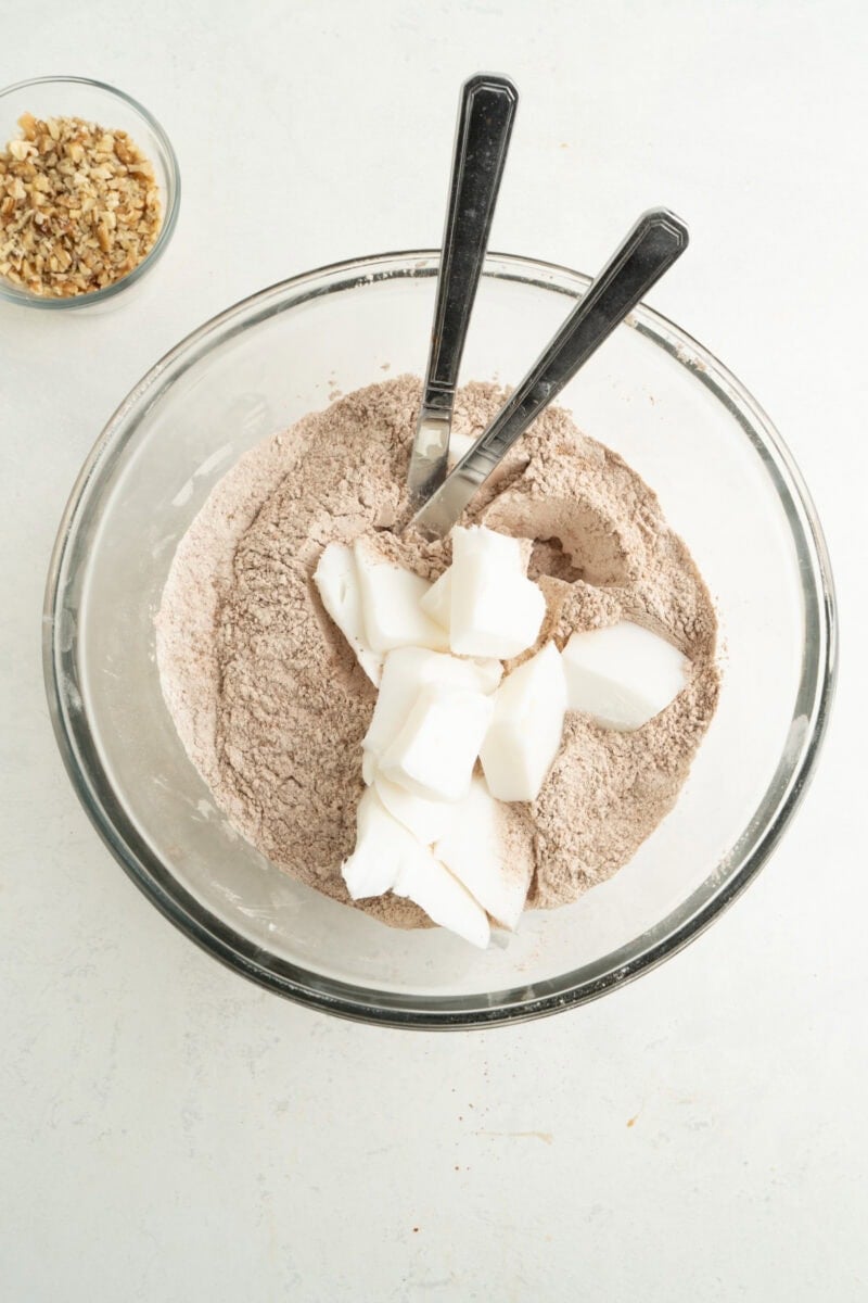 Shortening in a bowl with dry cookie mix along with two knives.
