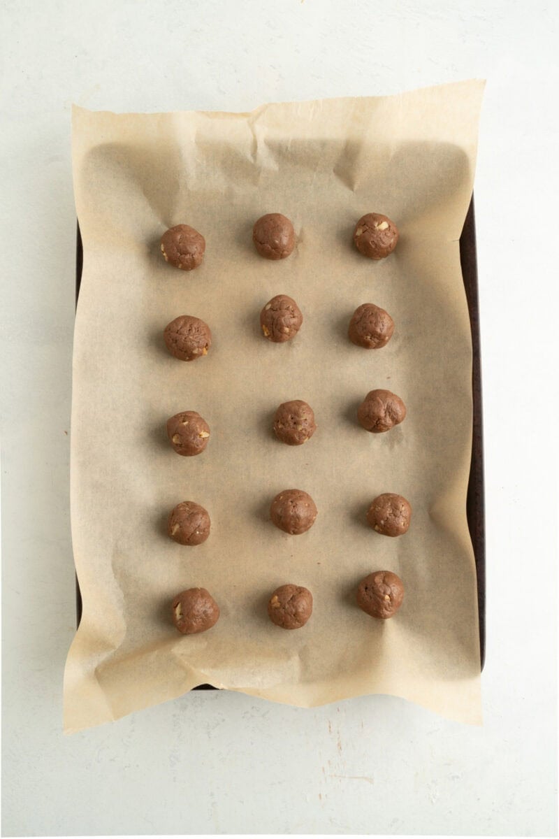 Balls of chocolate cookie dough on a baking sheet.